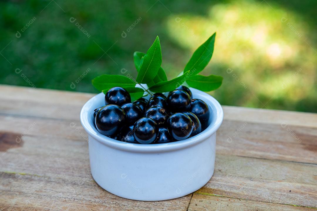 Jabuticabas sobre uma tigela branca mesa madeira