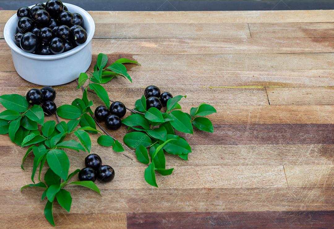 Jabuticaba sobre tigela mesa madeira folha verde