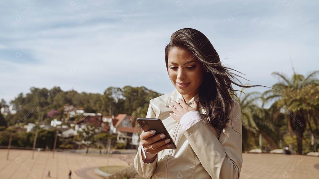 Linda jovem latina usando smartphone em pé na cidade st