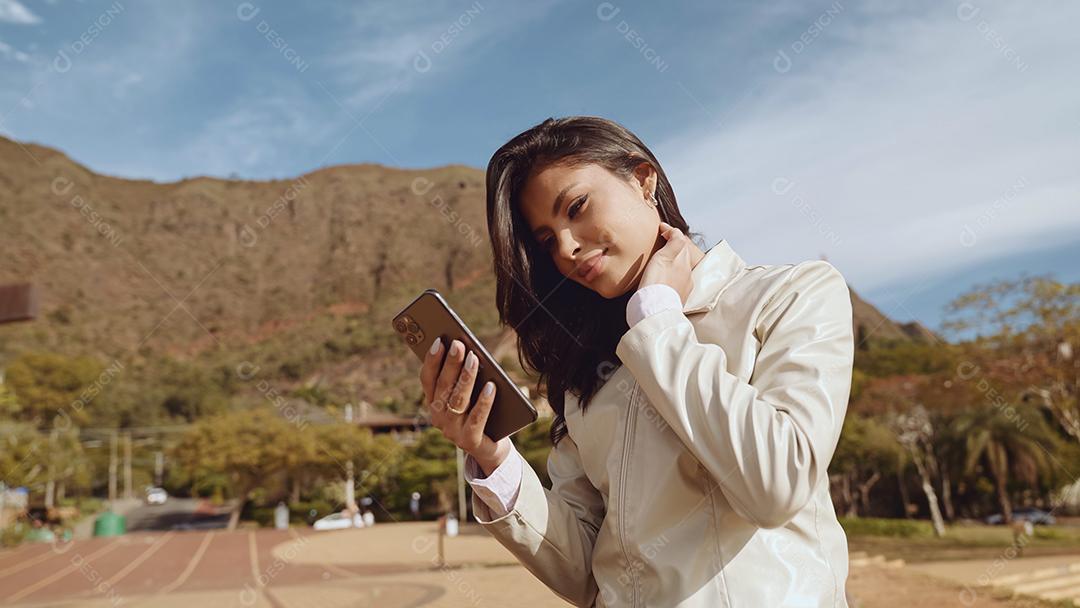 Linda jovem latina usando smartphone em pé na cidade st