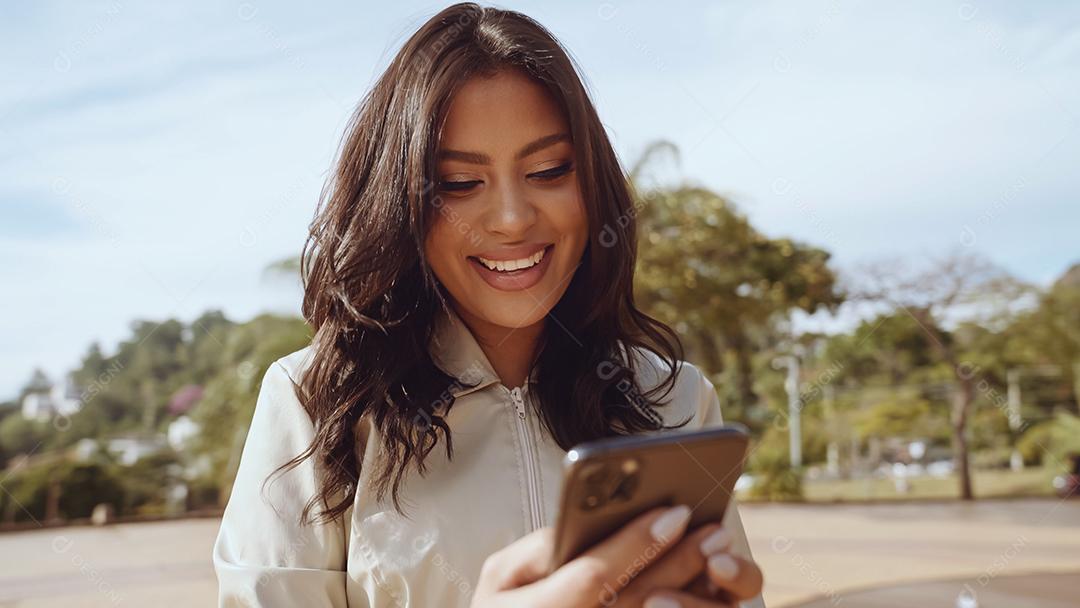 Linda jovem latina usando smartphone em pé na cidade st