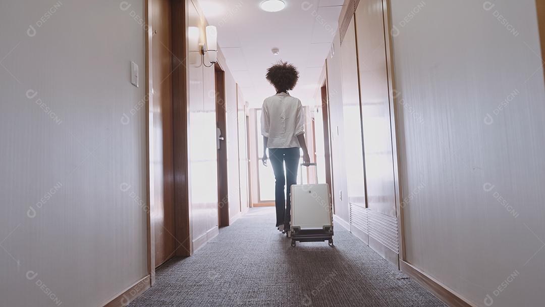 Woman with suitcase in the hallway at the hotel. Check in at the
