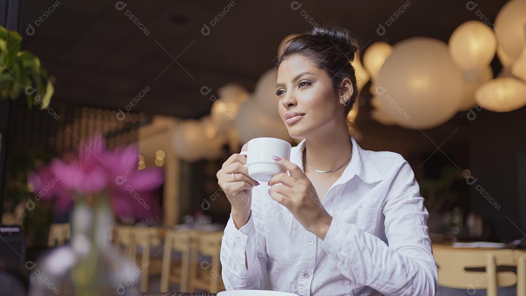 Mulher latina em um café bebendo café.