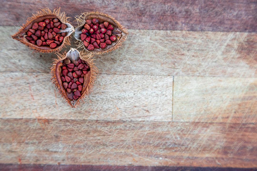 Urucum partido ao meio sobre uma mesa de madeira