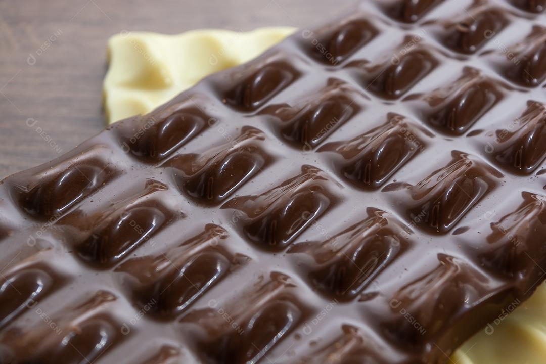 barra de chocolate escuro ou leitoso sobre barra de chocolate branco e madeira