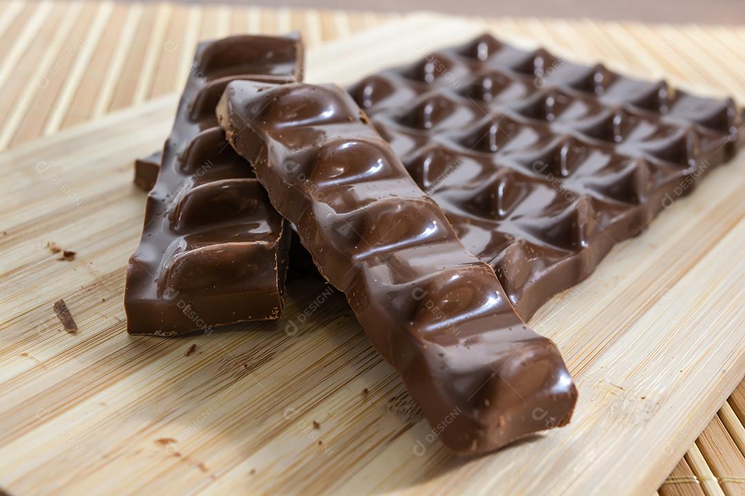 pedaços de chocolate, barra e fatias sobre tábua de madeira e b