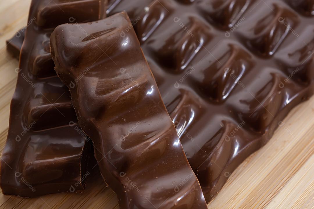 pedaços de chocolate, barra e fatias sobre tábua de madeira e b