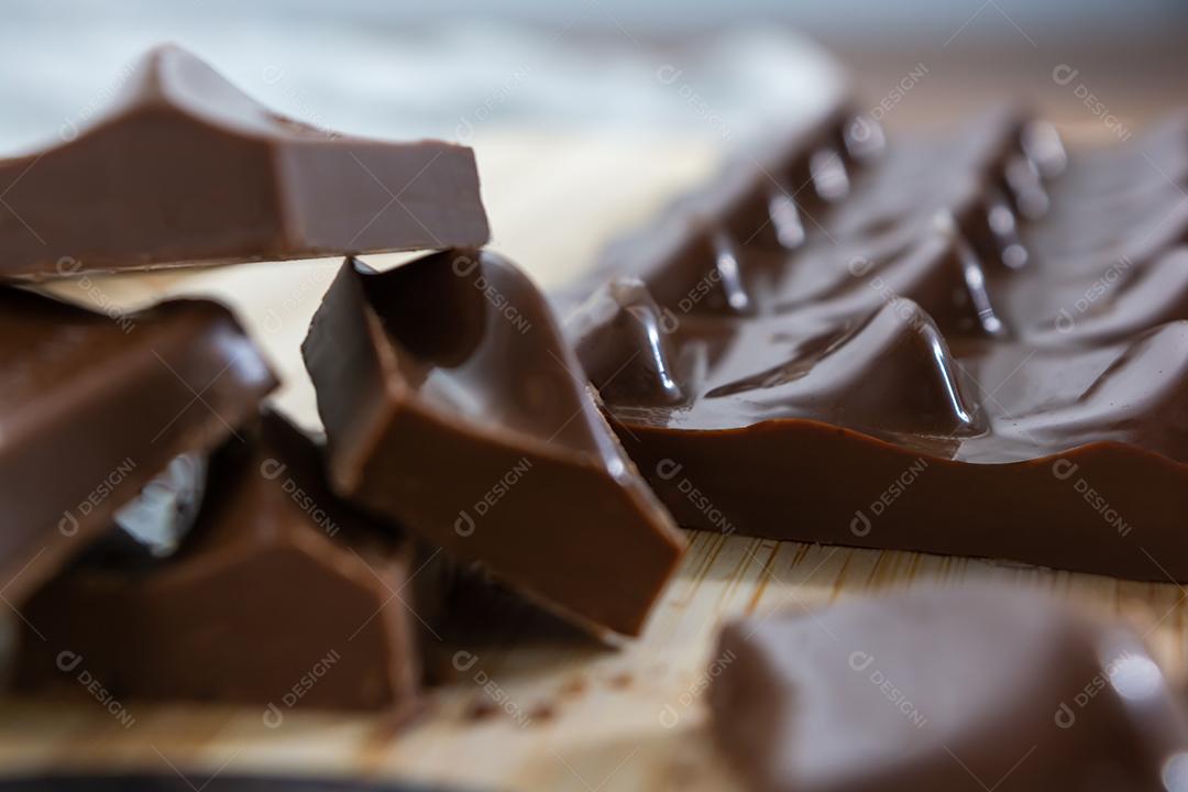 cortando pedaços de chocolate ao leite em uma tábua de madeira com