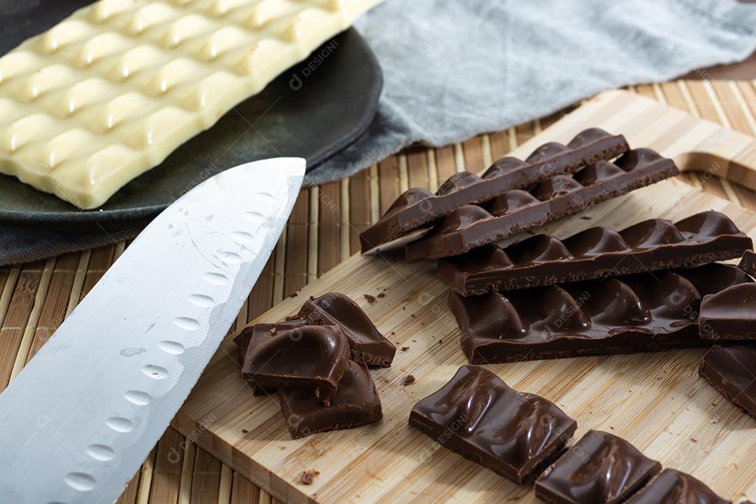 cortando pedaços de chocolate ao leite em uma tábua de madeira com