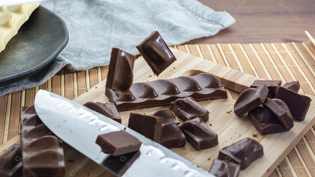 conceito cortando pedaços de chocolate ao leite escuro, com pedaços caindo