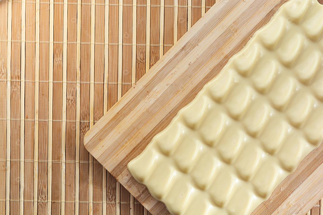 barra de chocolate branco e pedaços quadrados em uma tábua de madeira