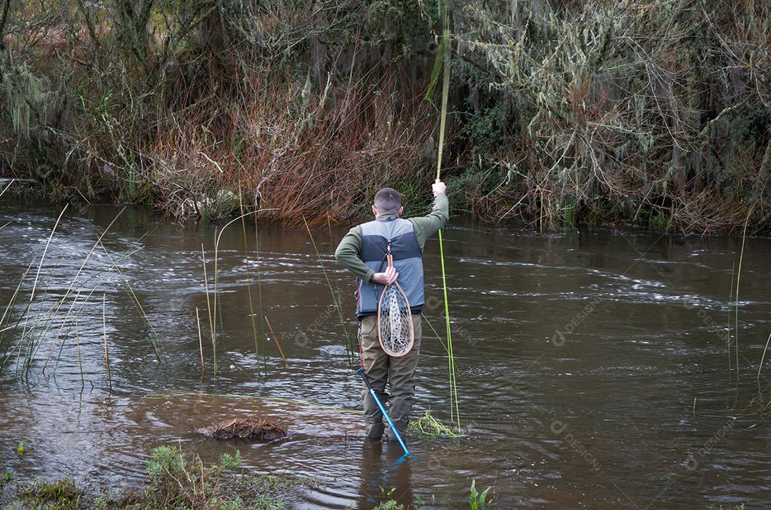 Pescador pesca truta arco-íris na montanha em belas paisagens.