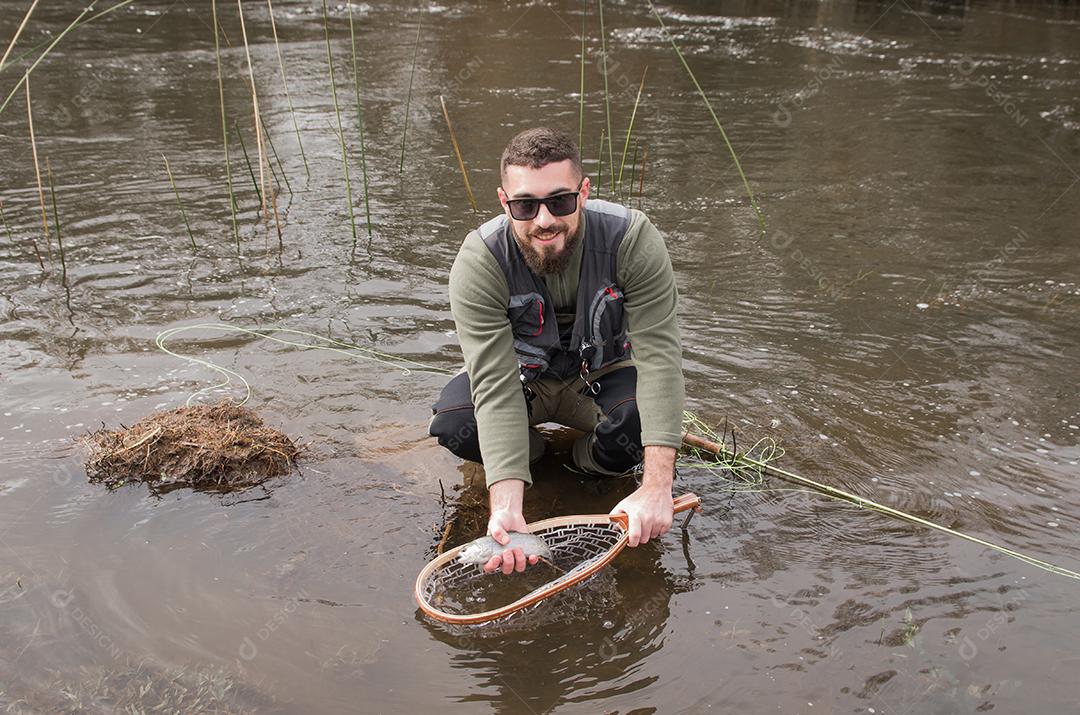 Pescador pesca truta arco-íris na montanha em belas paisagens.