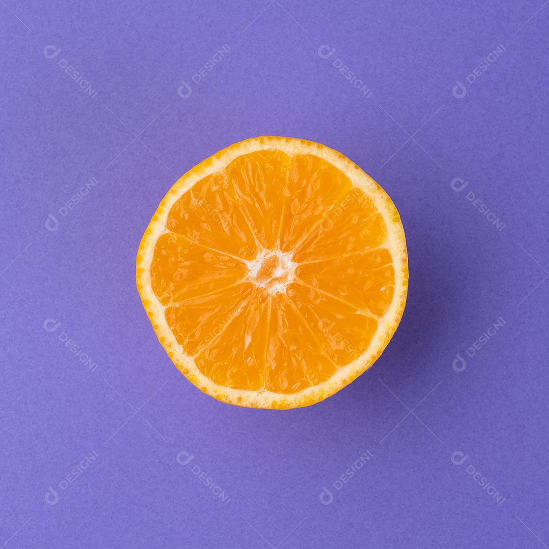 Metade laranja isolada sobre plano de fundo texturizado roxo