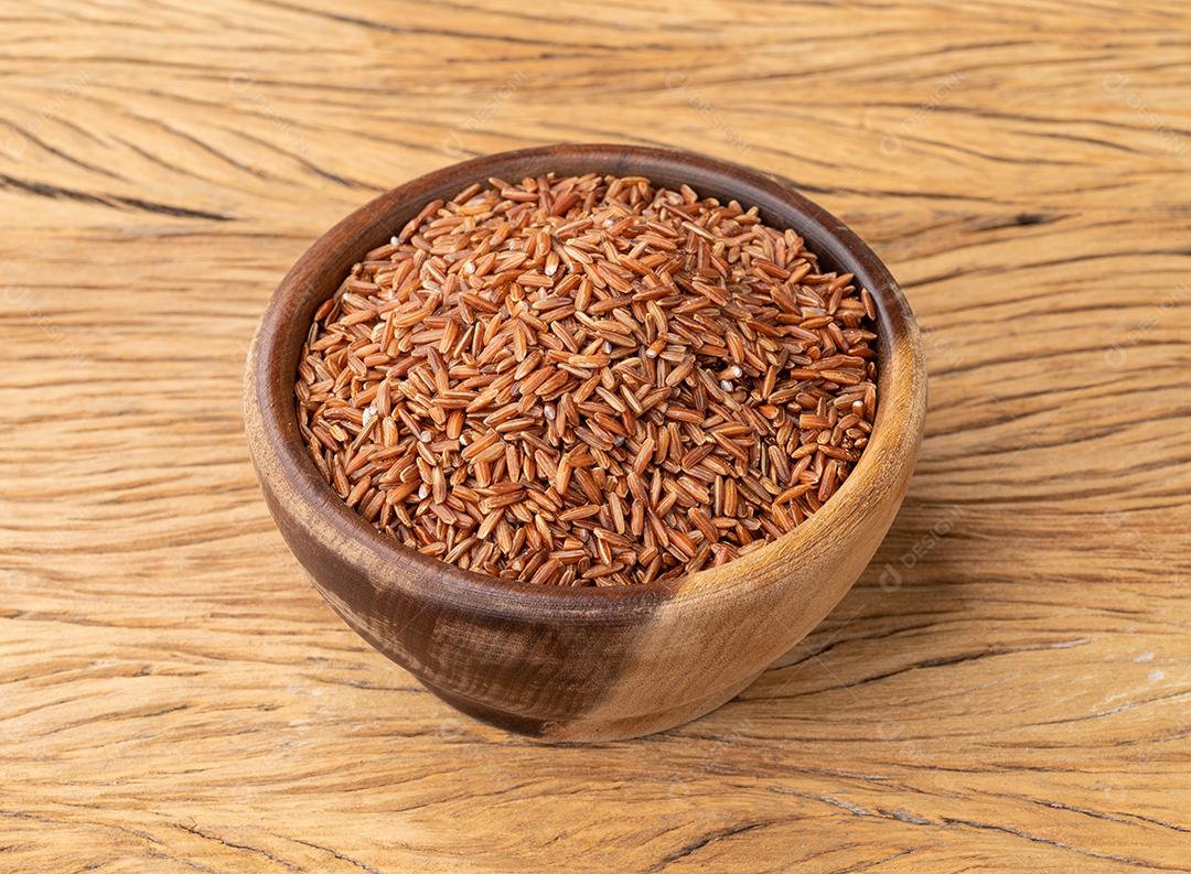 Arroz inteiro vermelho cru em uma tigela sobre a mesa de madeira