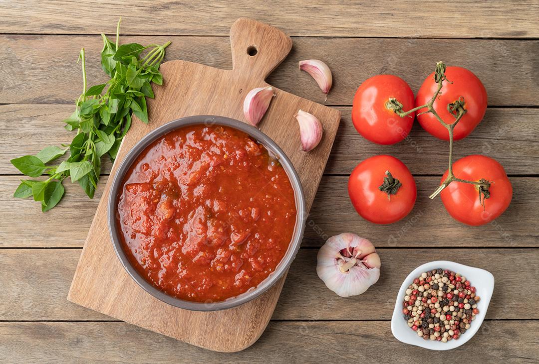 Molho de tomate, tomate, alho, azeite e ervas sobre madeira