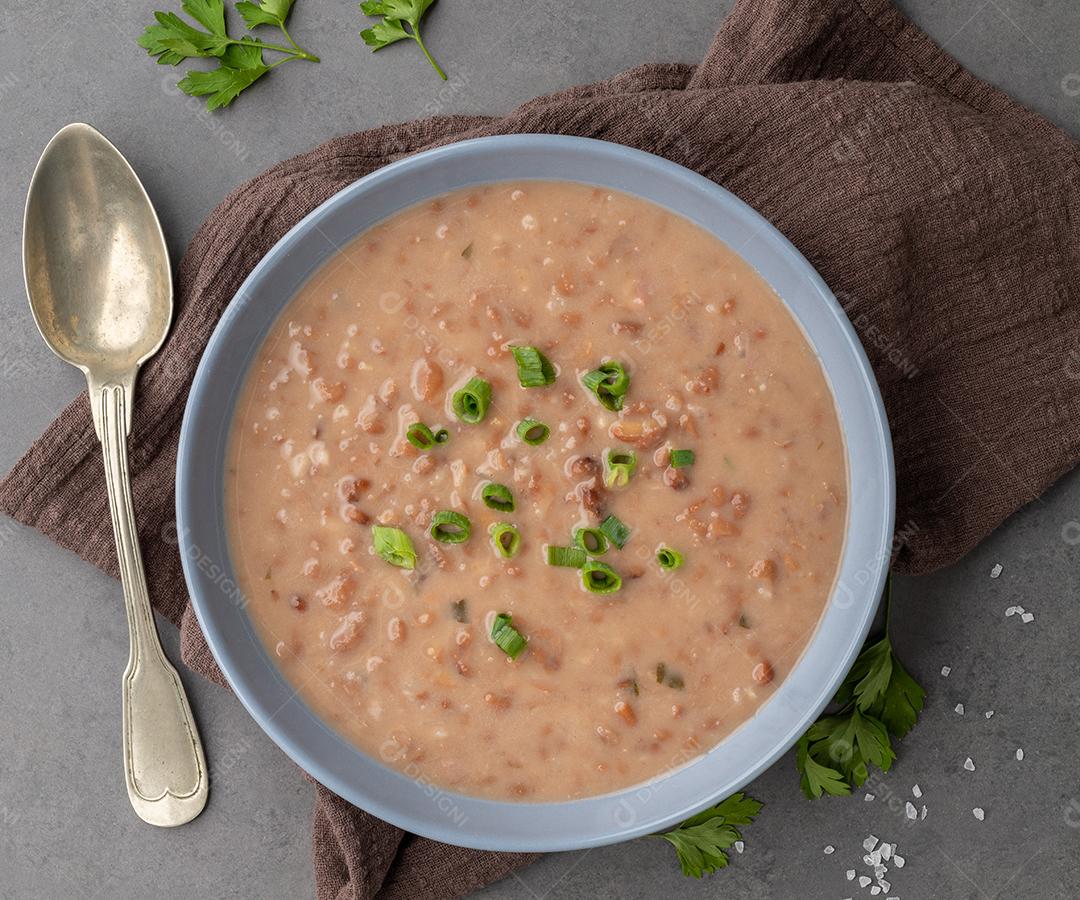 Sopa de lentilha em uma tigela com tempero sobre fundo de pedra