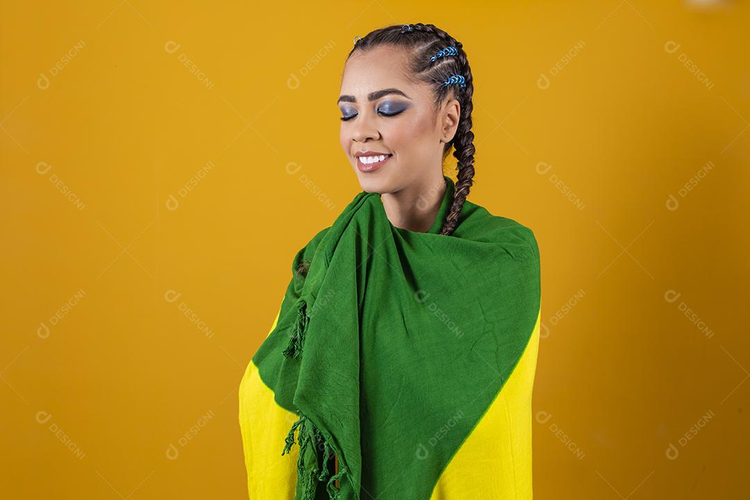 Fã brasileiro segurando a bandeira do Brasil em fundo cinza.