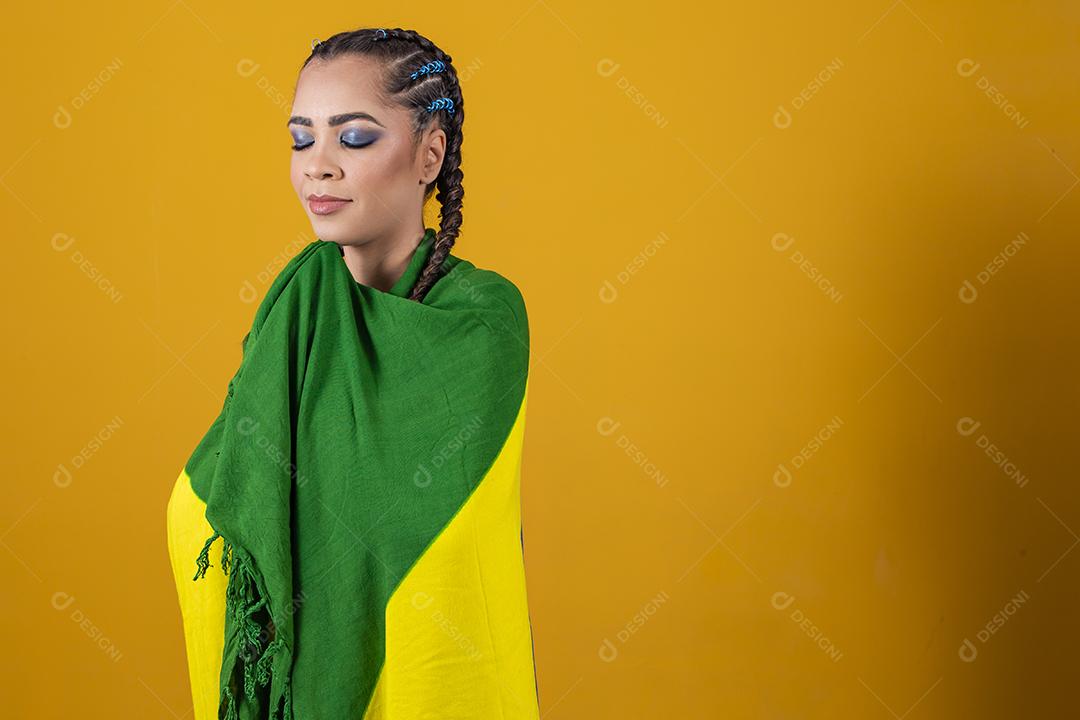 Fã brasileiro segurando a bandeira do Brasil em fundo cinza.