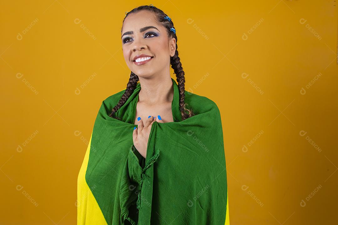 Fã brasileiro segurando a bandeira do Brasil em fundo cinza.