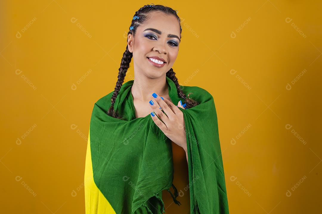 Fã brasileiro segurando a bandeira do Brasil em fundo cinza.