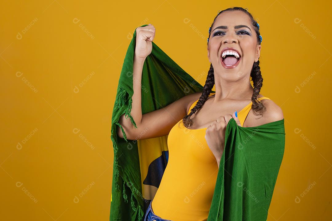 Fã brasileiro segurando a bandeira do Brasil em fundo cinza.