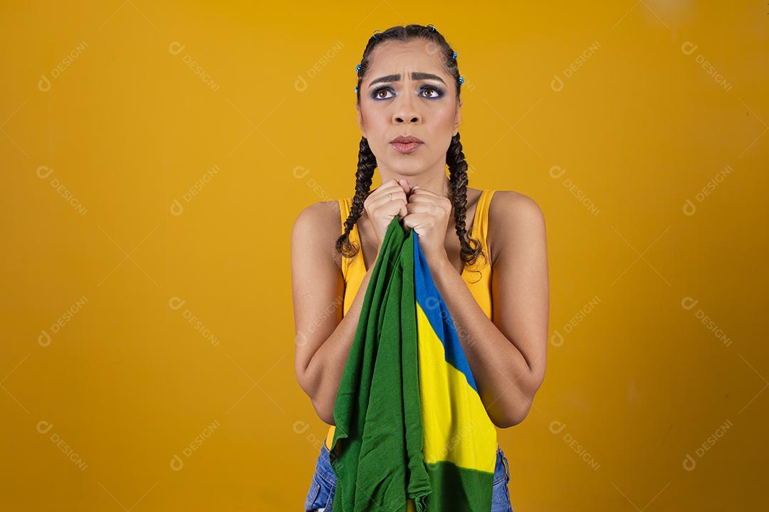 Fã brasileiro segurando a bandeira do Brasil em fundo cinza.