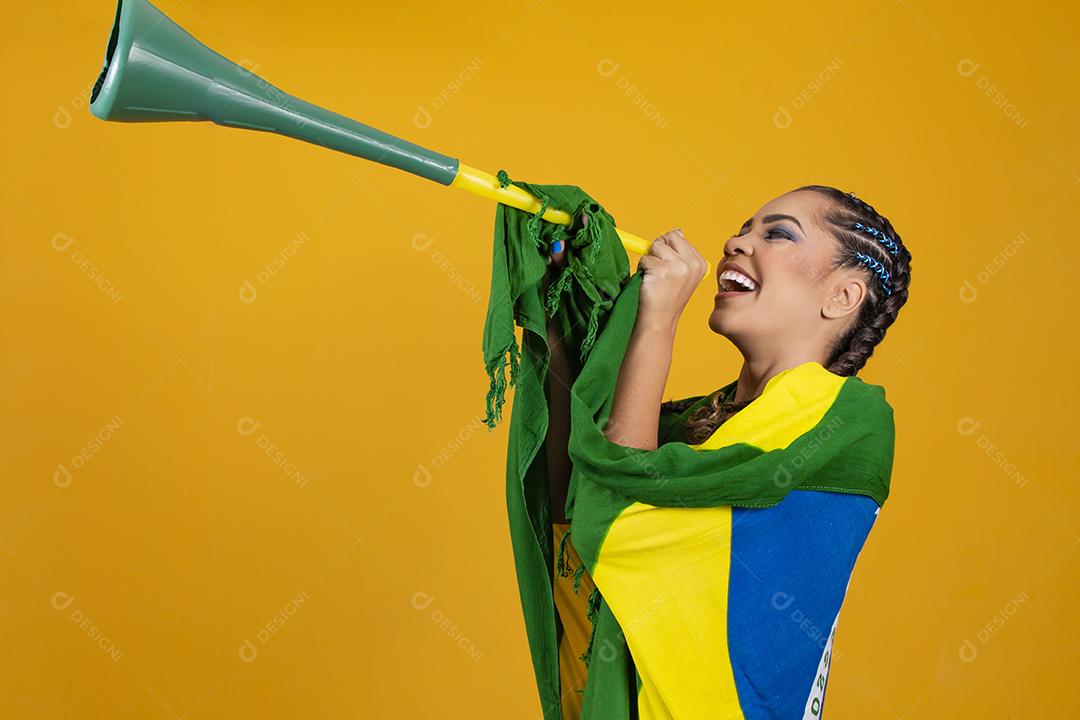 Líder de torcida brasileira jovem com uma vuvuzela em backg amarelo
