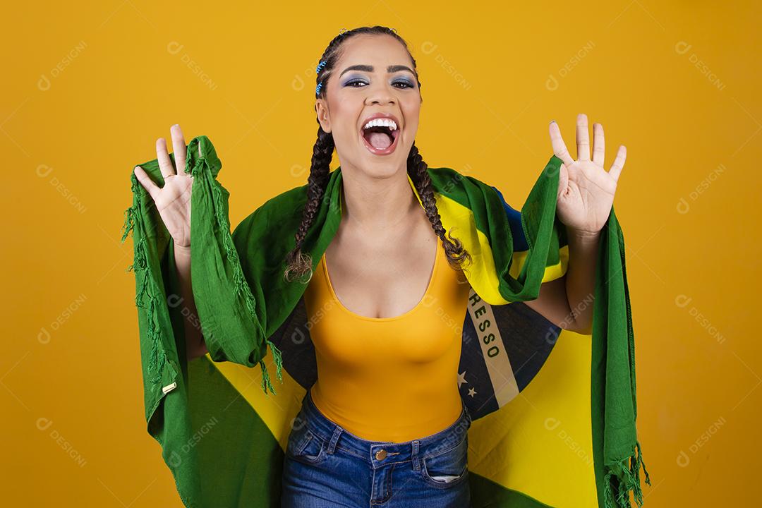 Torcedora brasileira. Fã brasileira comemorando partida de futebol em fundo cinza.