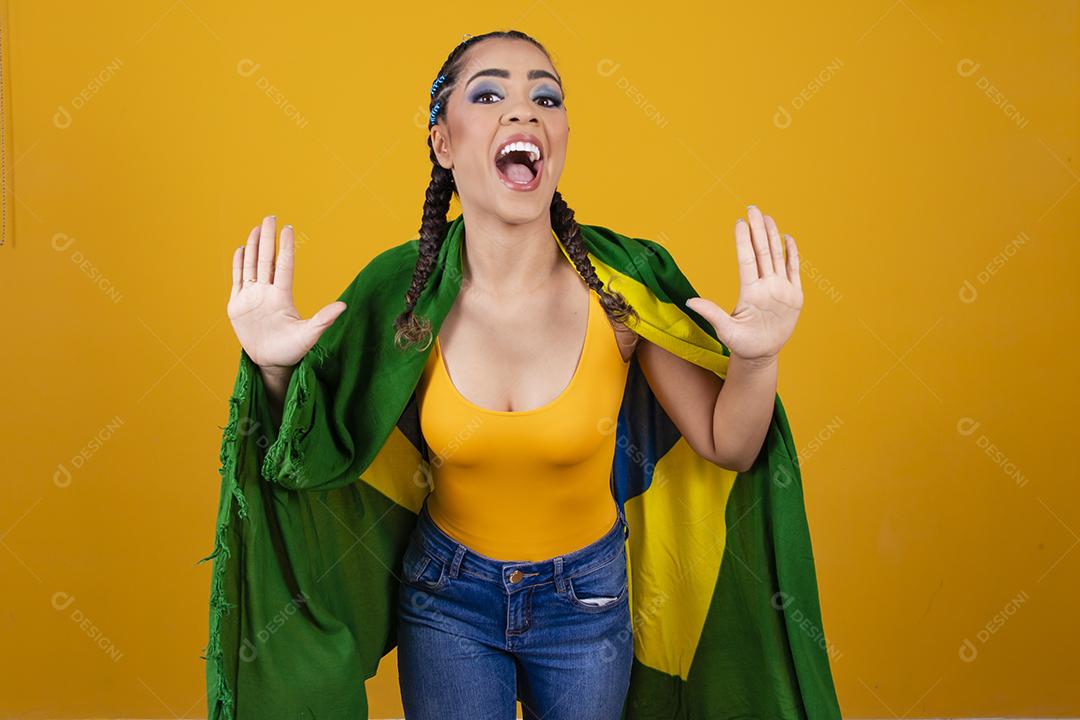 Torcedora brasileira. Fã brasileira comemorando partida de futebol em fundo cinza.