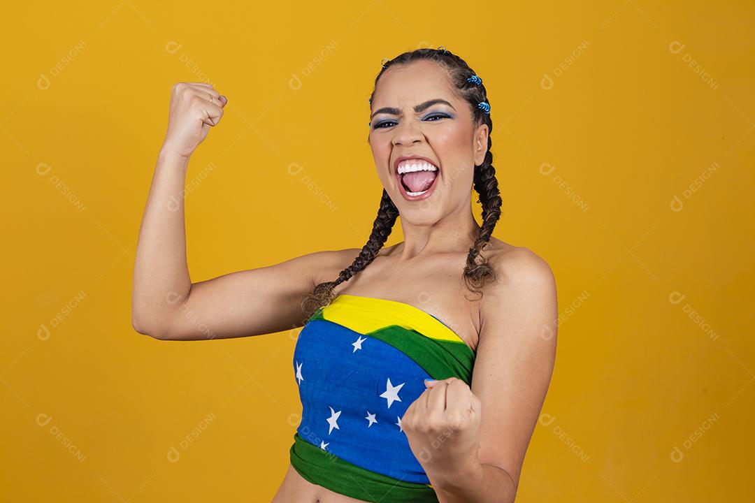 Torcedora brasileira. Fã brasileira comemorando partida de futebol em fundo cinza.