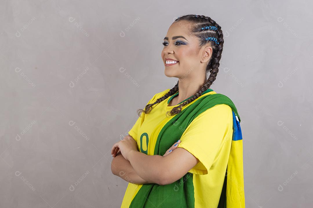 Torcedora brasileira. Fã brasileira comemorando partida de futebol em fundo cinza.