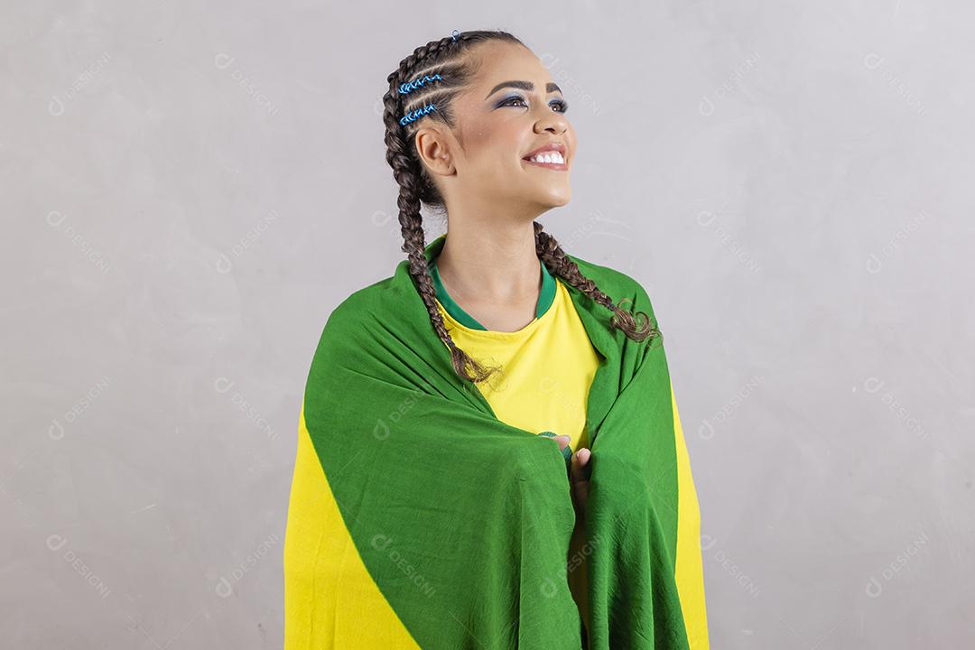 Torcedora brasileira. Fã brasileira comemorando partida de futebol em fundo cinza.