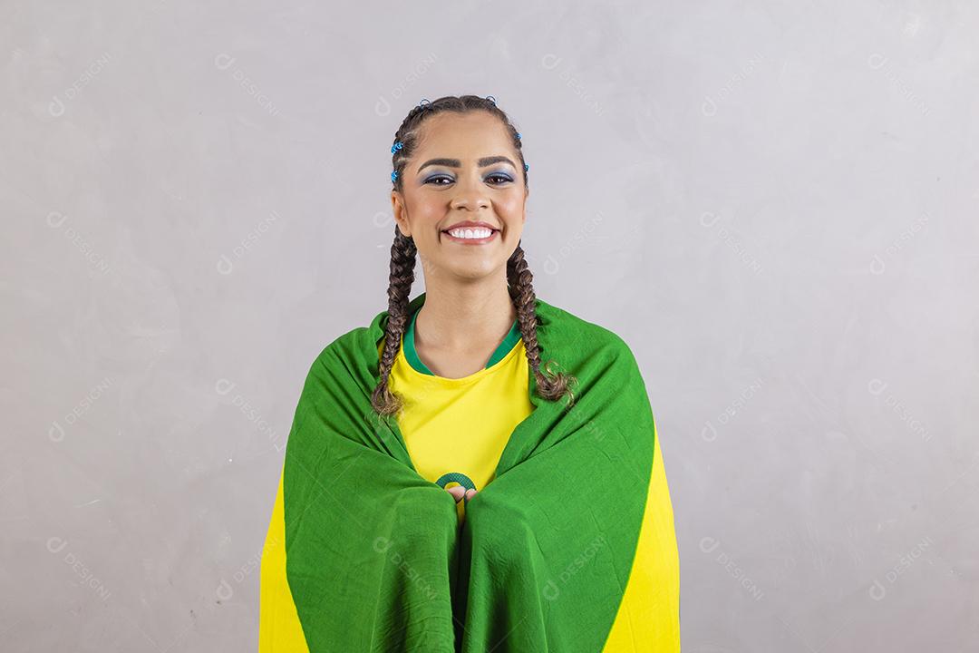 Torcedora brasileira. Fã brasileira comemorando partida de futebol em fundo cinza.
