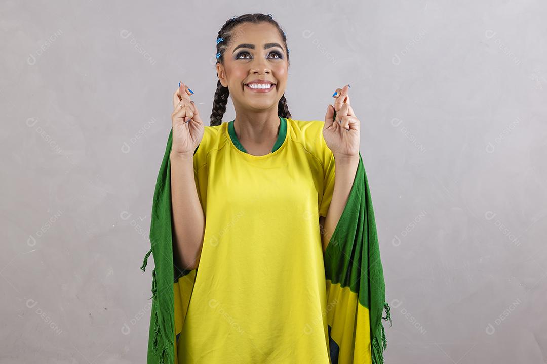 Torcedora brasileira. Fã brasileira comemorando partida de futebol em fundo cinza.