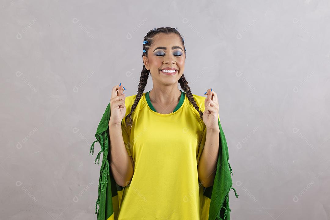 Torcedora brasileira. Fã brasileira comemorando partida de futebol em fundo cinza.