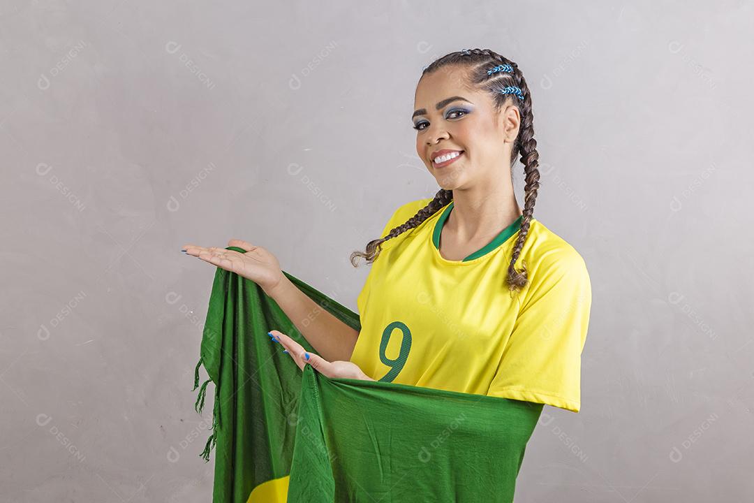 Torcedora brasileira. Fã brasileira comemorando partida de futebol em fundo cinza.