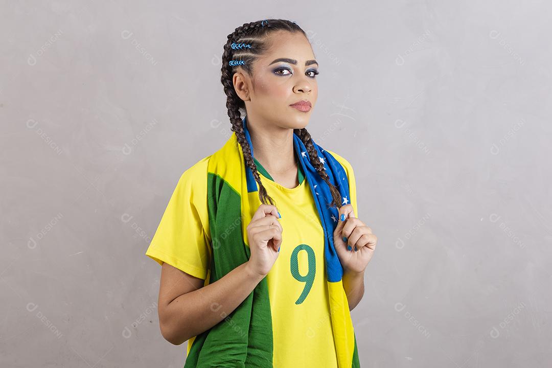 Torcedora brasileira. Fã brasileira comemorando partida de futebol em fundo cinza.