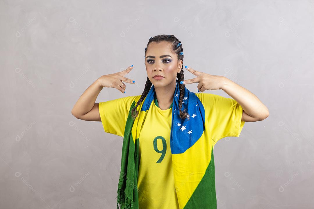 Torcedora brasileira. Fã brasileira comemorando partida de futebol em fundo cinza.