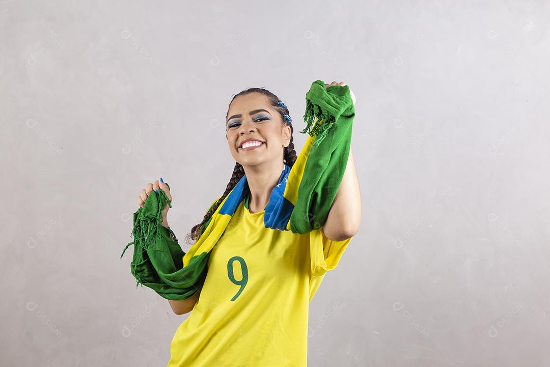 Torcedora brasileira. Fã brasileira comemorando partida de futebol em fundo cinza.