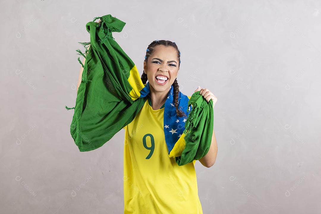 Torcedora brasileira. Fã brasileira comemorando partida de futebol em fundo cinza.