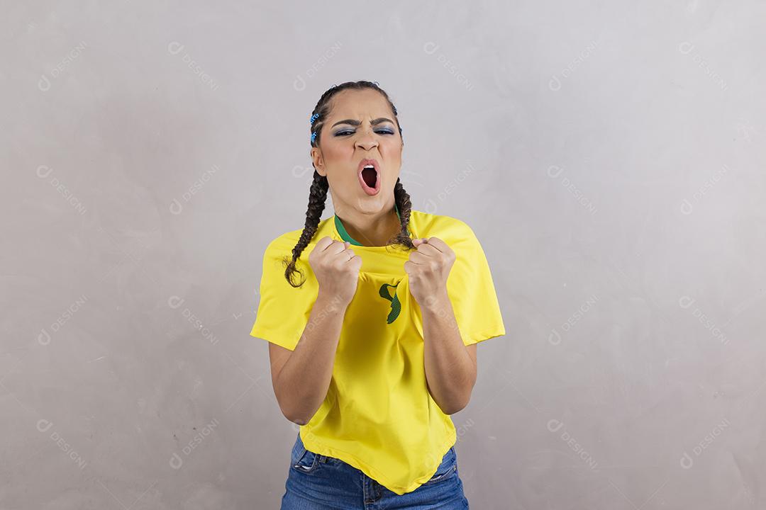 Torcedora brasileira. Fã brasileira comemorando partida de futebol em fundo cinza.