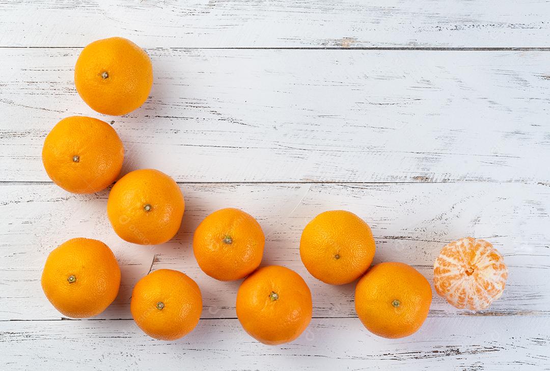 Tangerinas com frutas cortadas sobre mesa de madeira com espaço de cópia