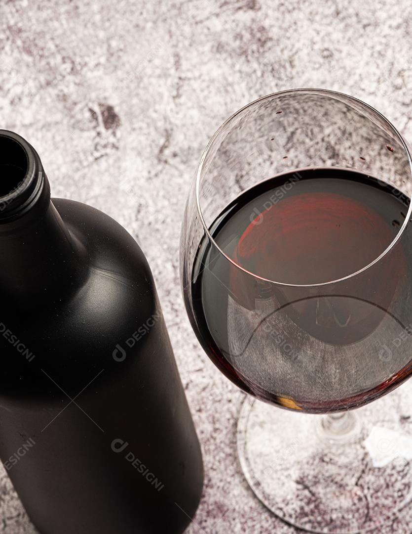 vinho tinto servido em um copo de cristal com uma garrafa ao lado e saca-rolhas.