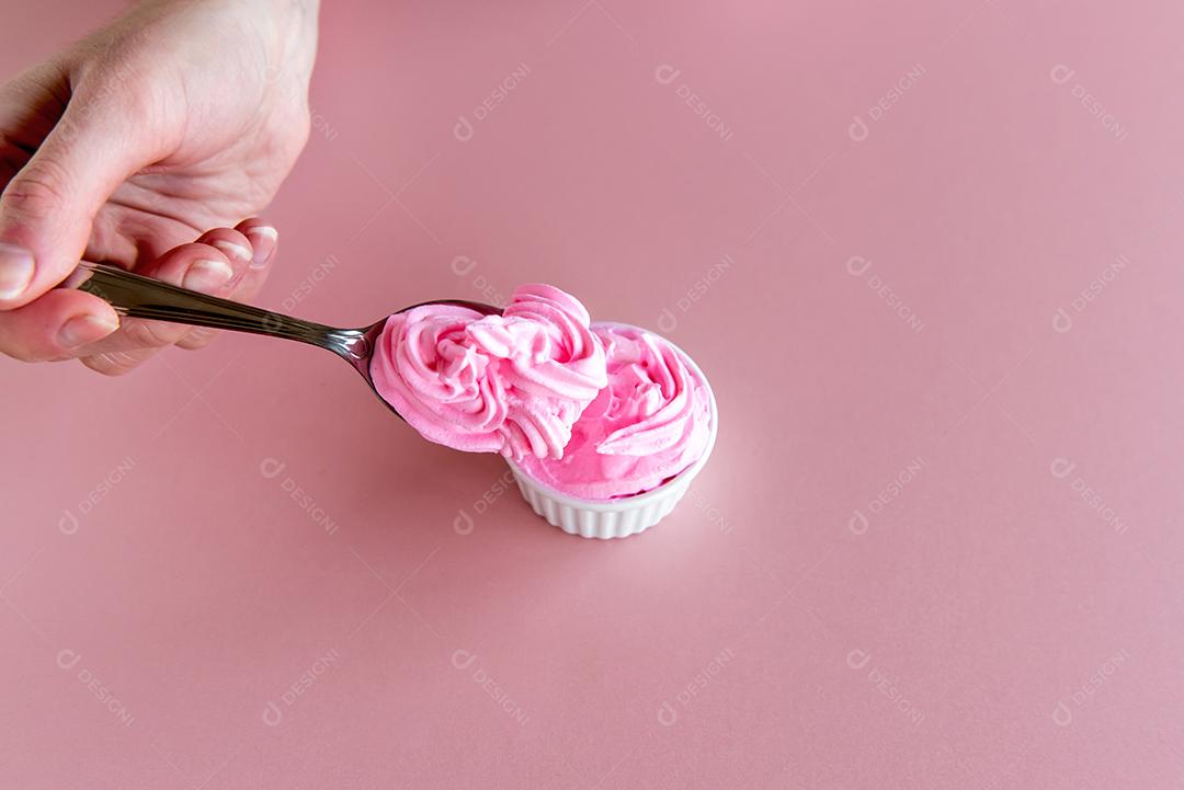 mão segurando a colher com chantilly rosa