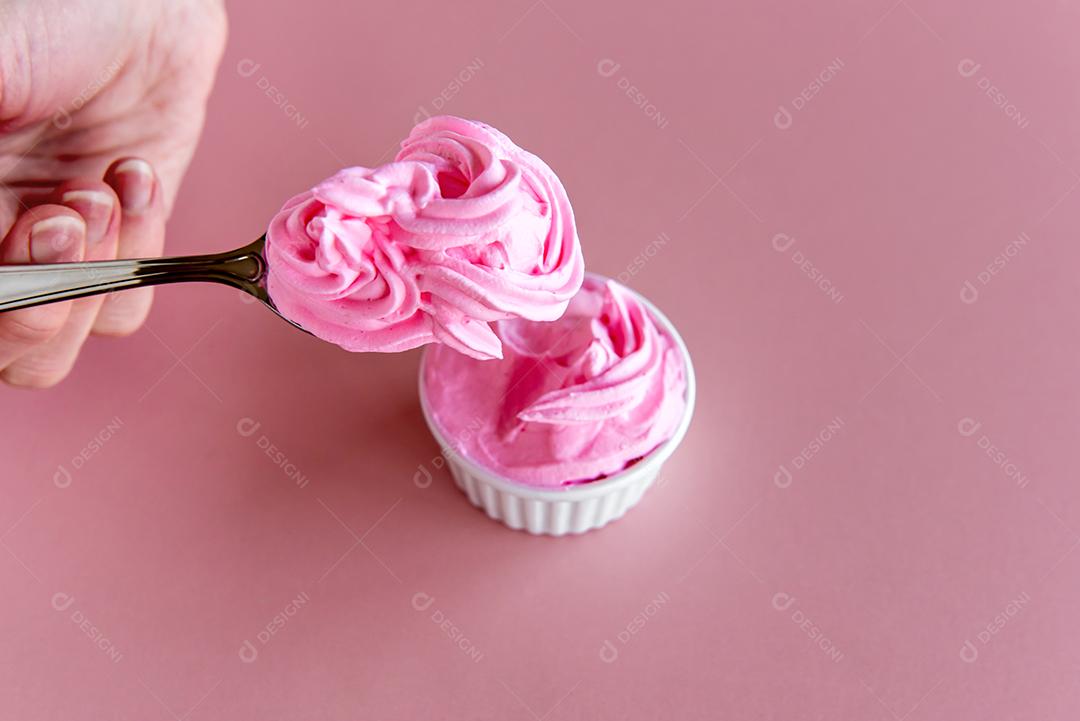 mão segurando a colher com chantilly rosa