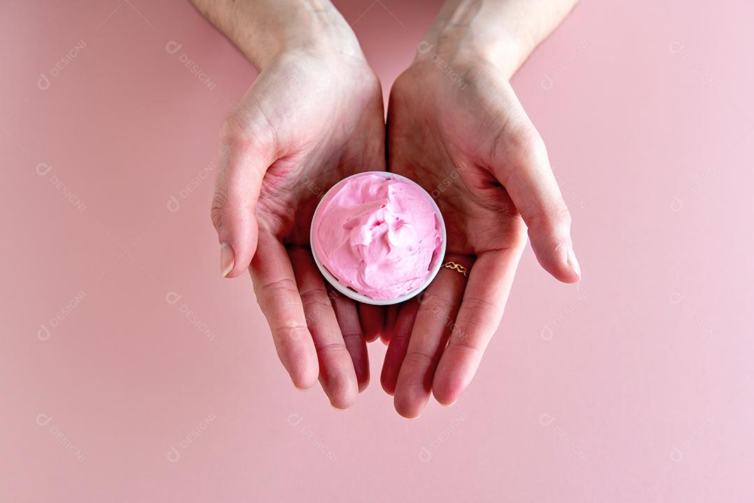 mãos segurando uma tigela com chantilly rosa.