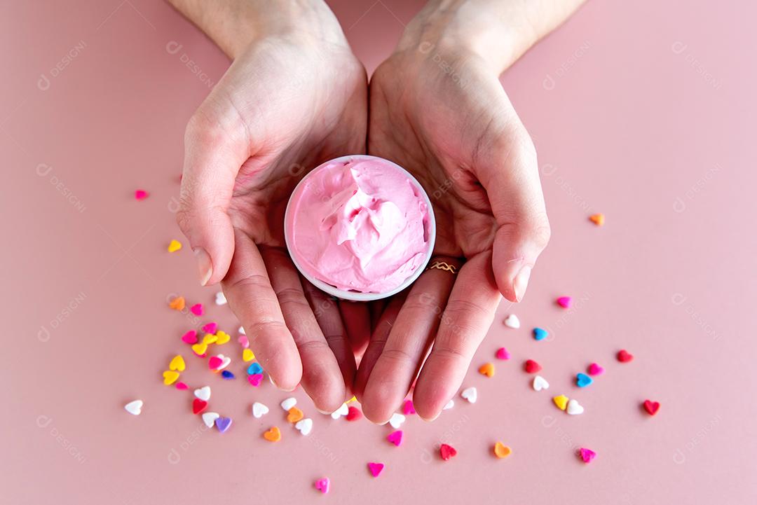 mãos segurando uma tigela com chantilly rosa.