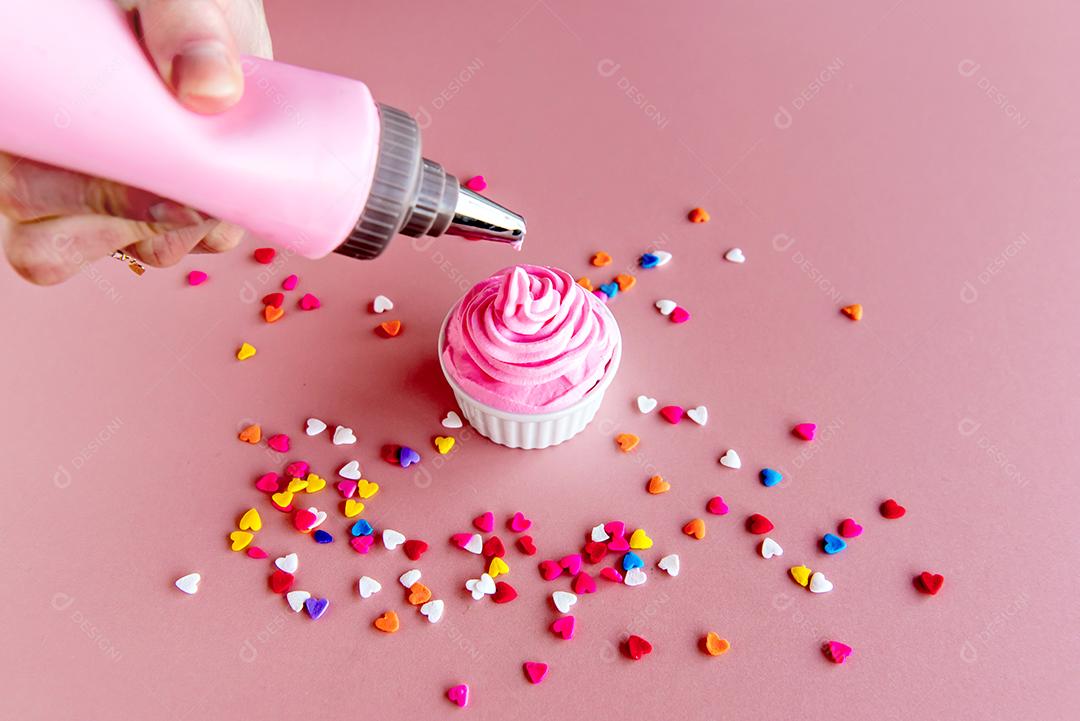 saco de confeitar colocando chantilly rosa na colher.