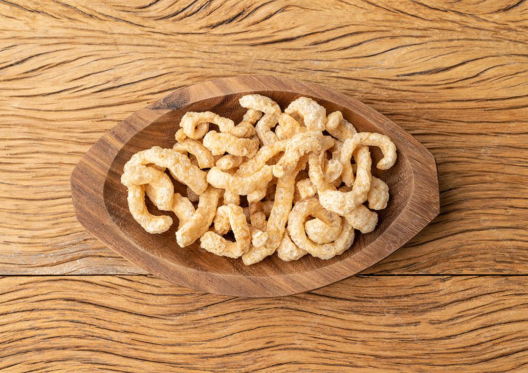 Torresmo de pele de porco frito em um prato sobre a mesa de madeira